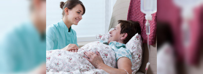 elderly woman lying in bed with her caregiver